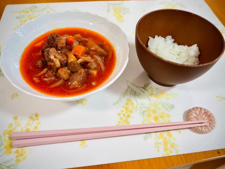 トマト味の煮込みとごはんを並べた一膳